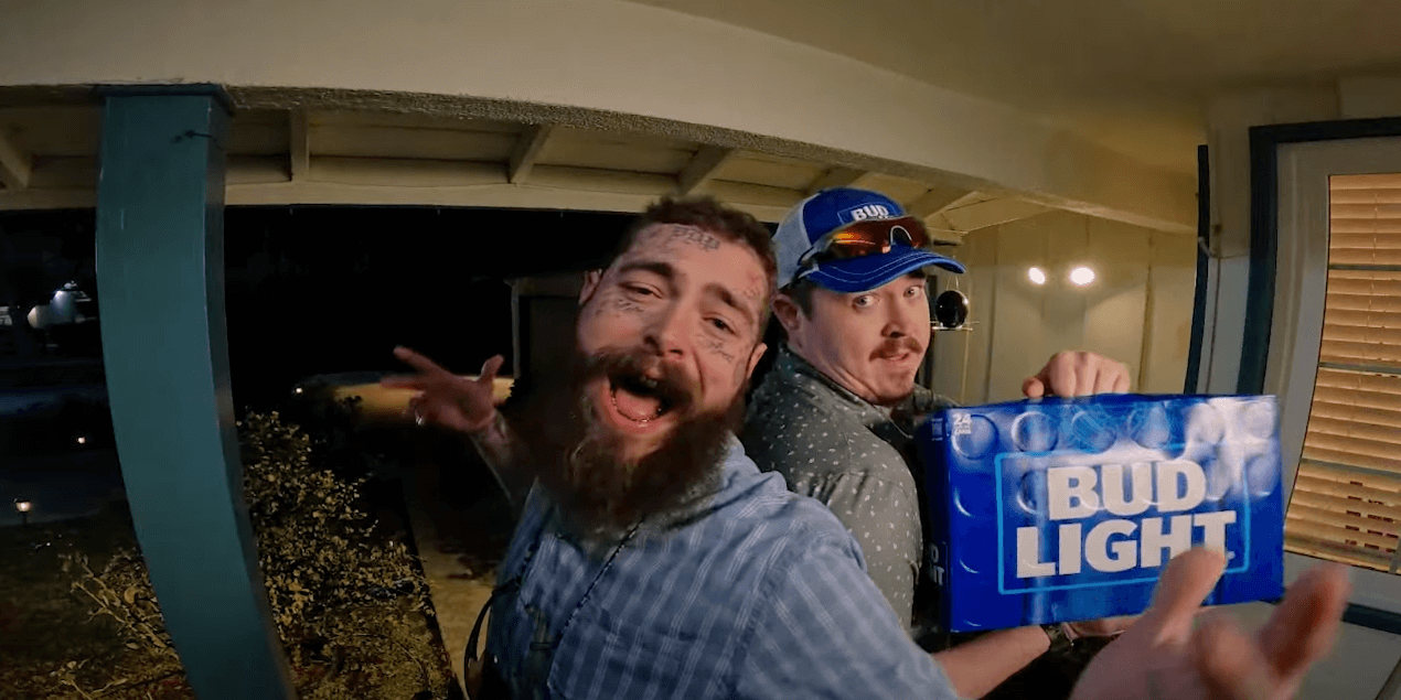 Post Malone and Shane Gillis at a doorway with a box of Bud Light.